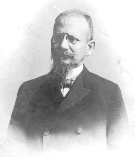 A person with a beard wearing a suit and tie

Description automatically generated